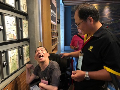 院生阿斌看到滿牆的陶藝作品+++雖然口語無法表達++但興奮之情全寫在臉上++右為八里扶輪社社長杜燕輝