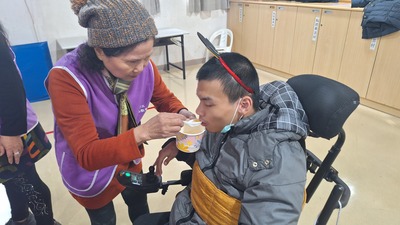 八里愛心教養院志工為院生準備暖呼呼的湯圓，志工秋菊阿姨(左)一口一口餵著院生