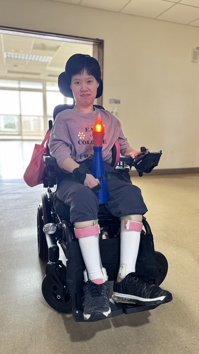 八里愛心教養院運動會規劃聖火進場，由重度腦性麻痺院生小貞擔任火炬手