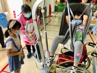 參加八里愛心體驗營的學童透過轉移位機從床上到輪椅上